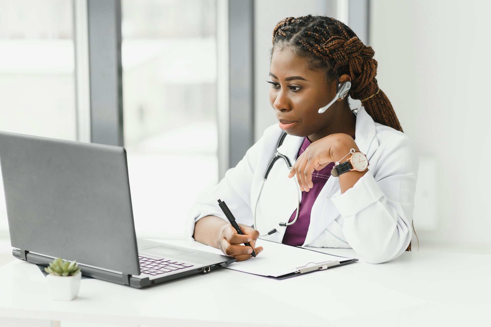 African American woman doctor working at her office online using portable inormation device