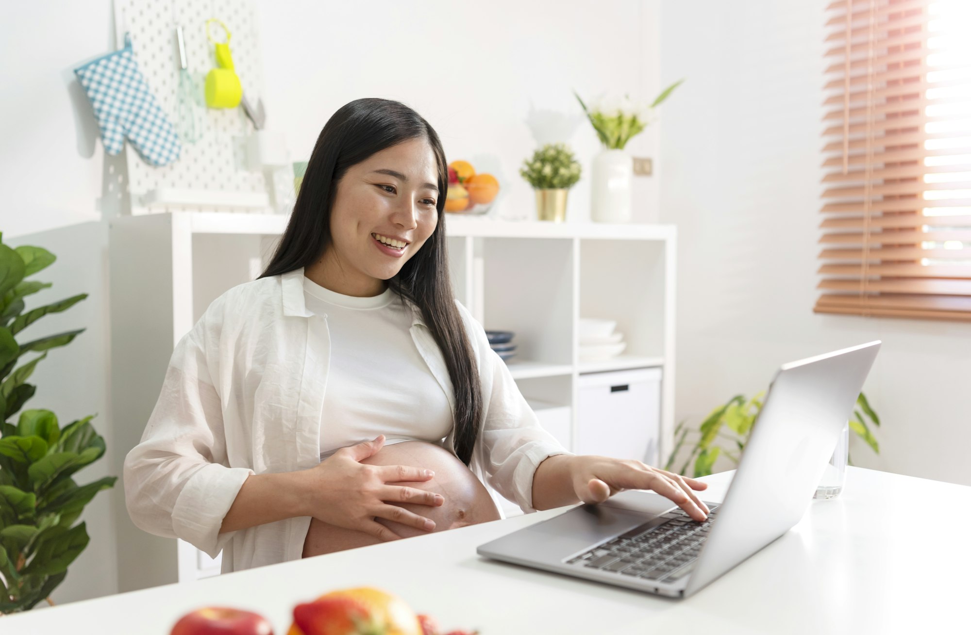 Pregnant woman using laptop at home.